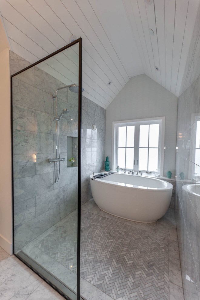 Стильный дизайн: большая главная ванная комната, совмещенная с туалетом в стиле кантри с фасадами в стиле шейкер, серыми фасадами, отдельно стоящей ванной, душевой комнатой, серой плиткой, мраморной плиткой, серыми стенами, мраморным полом, врезной раковиной, столешницей из искусственного кварца, серым полом, открытым душем, белой столешницей, тумбой под одну раковину, встроенной тумбой, сводчатым потолком и стенами из вагонки - последний тренд