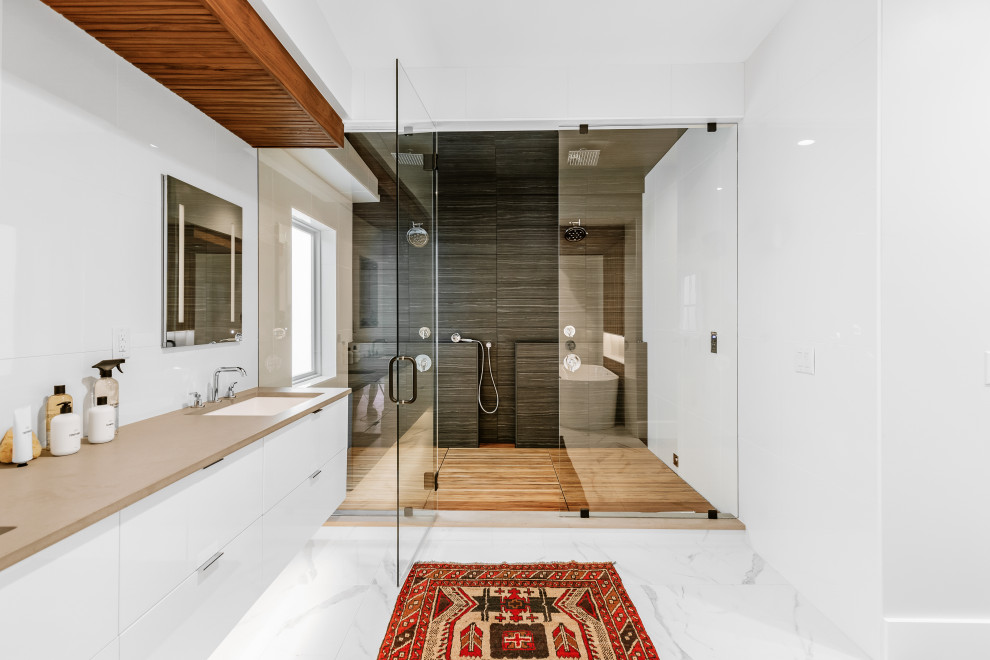 Inspiration for an industrial bathroom in Denver with flat-panel cabinets, white cabinets, a curbless shower, gray tile, white walls, an undermount sink, white floor, a hinged shower door, brown benchtops, a double vanity and a floating vanity.