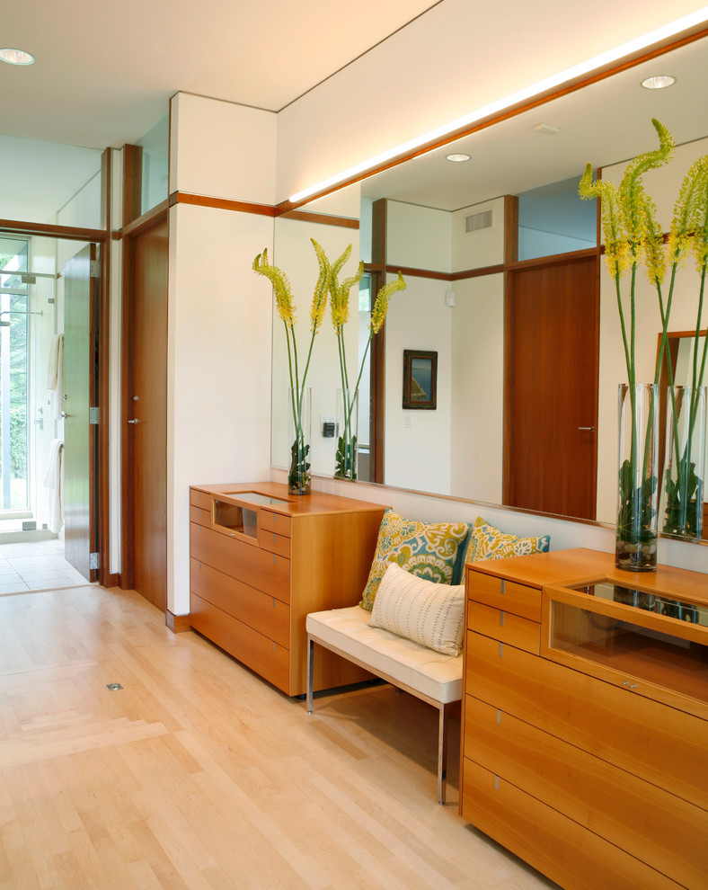 Photo of an expansive contemporary gender-neutral dressing room in Other with flat-panel cabinets, medium wood cabinets, light hardwood floors and brown floor.