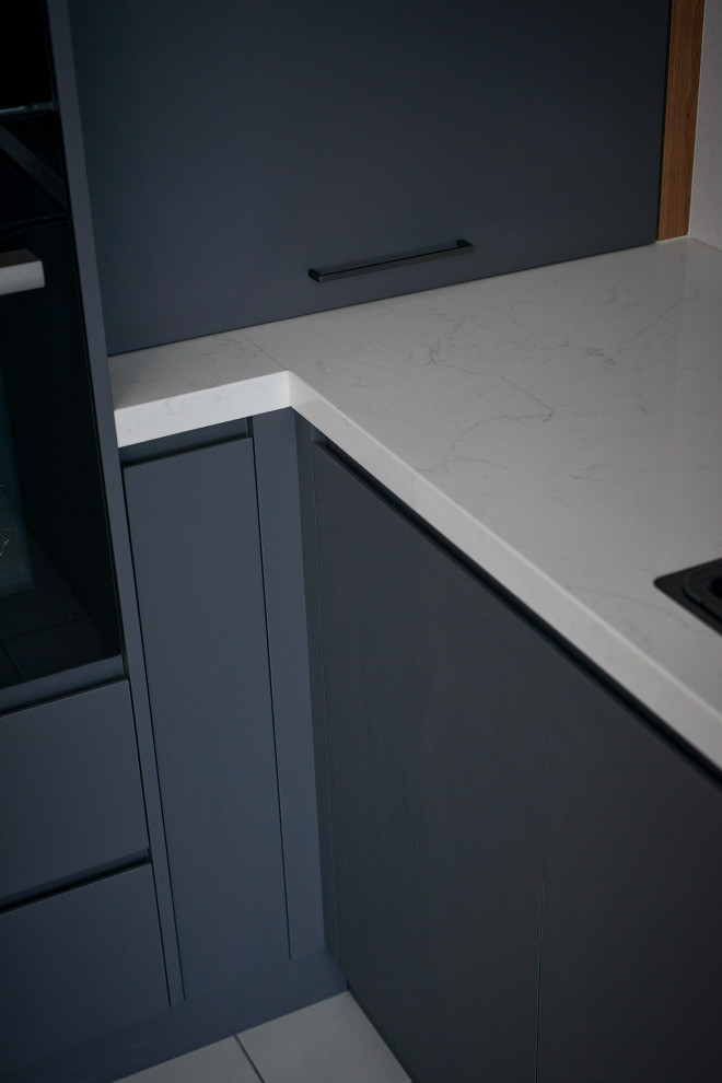 Design ideas for a mid-sized modern l-shaped open plan kitchen in Sydney with a drop-in sink, flat-panel cabinets, grey cabinets, quartz benchtops, multi-coloured splashback, mirror splashback, black appliances, porcelain floors, with island, yellow floor and white benchtop.