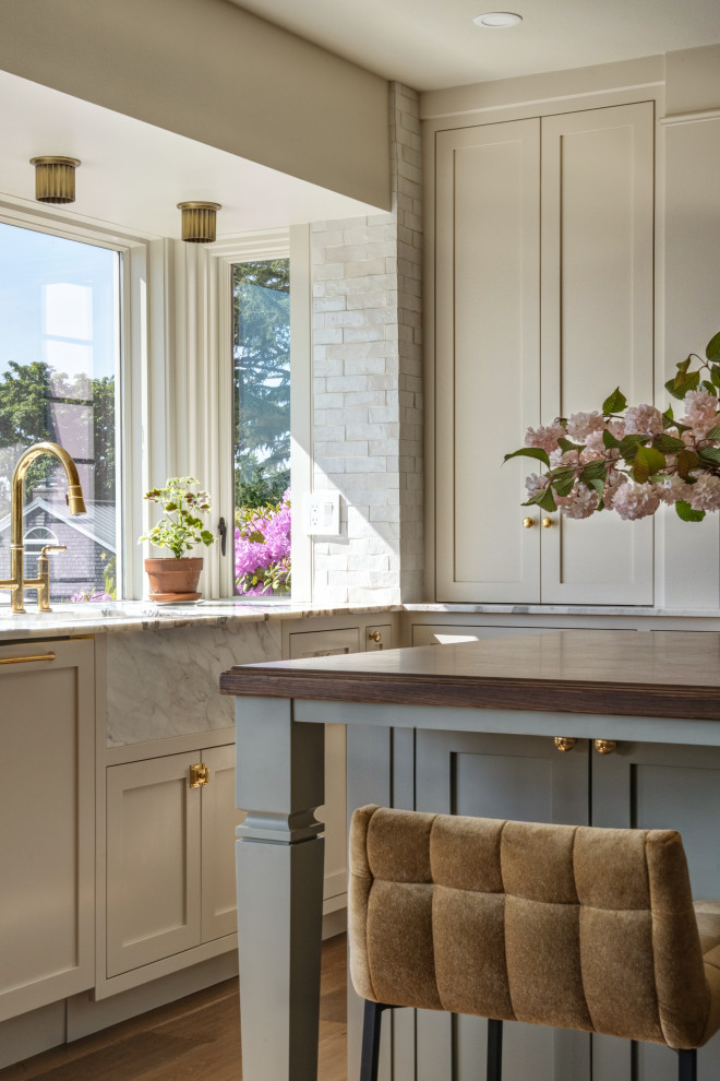 Eat-in kitchen - large traditional medium tone wood floor and brown floor eat-in kitchen idea in Seattle with an integrated sink, shaker cabinets, beige cabinets, marble countertops, marble backsplash, an island and white countertops