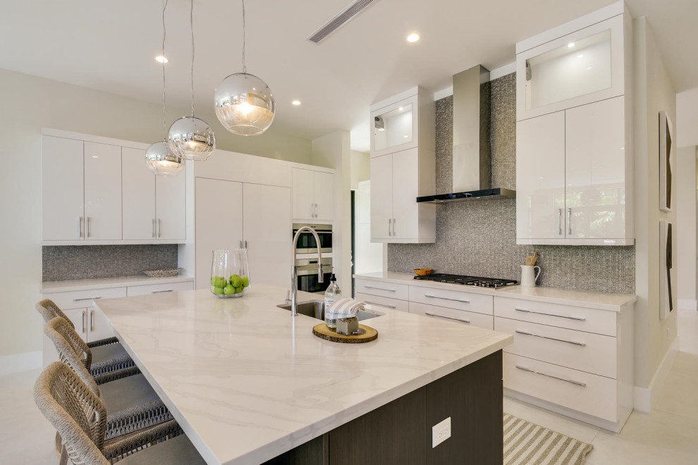 Example of a minimalist u-shaped porcelain tile and white floor kitchen design in Miami with an undermount sink, flat-panel cabinets, white cabinets, marble countertops, multicolored backsplash, mosaic tile backsplash, stainless steel appliances, an island and white countertops