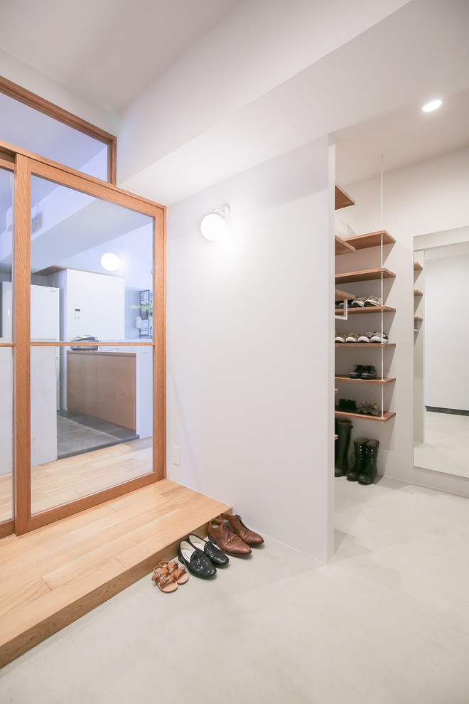 Photo of a modern entryway in Nagoya with white walls, concrete floors and grey floor.