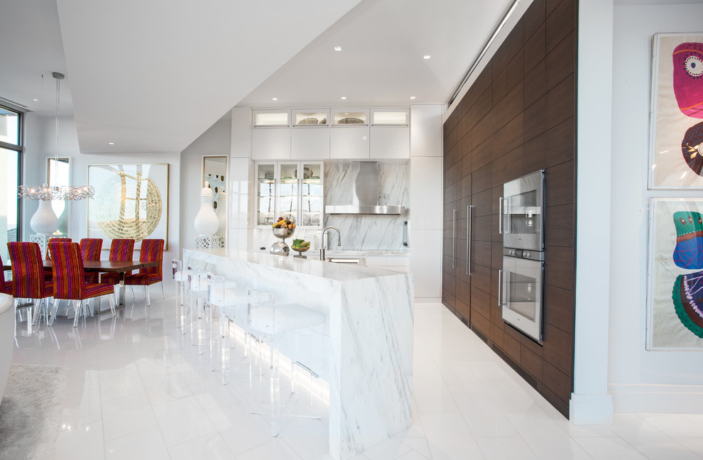 Inspiration for a contemporary l-shaped open plan kitchen in Other with flat-panel cabinets, white cabinets, white splashback, stone slab splashback, stainless steel appliances and with island.