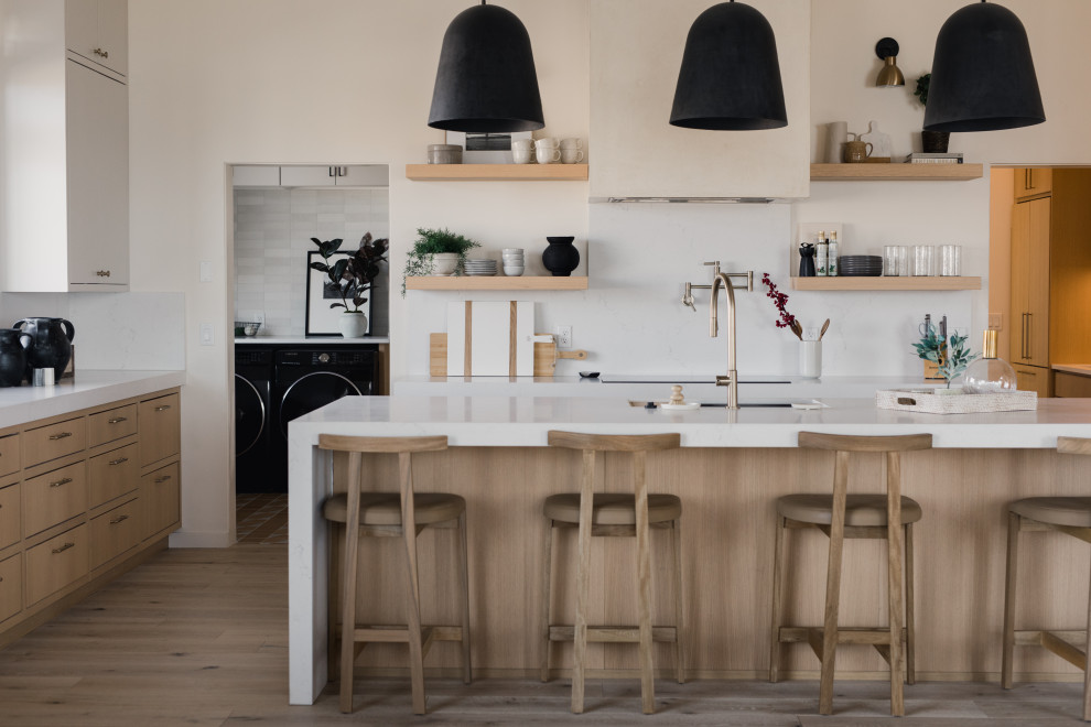 Photo of a scandinavian eat-in kitchen in Salt Lake City with an undermount sink, flat-panel cabinets, marble splashback, medium hardwood floors, with island and exposed beam.