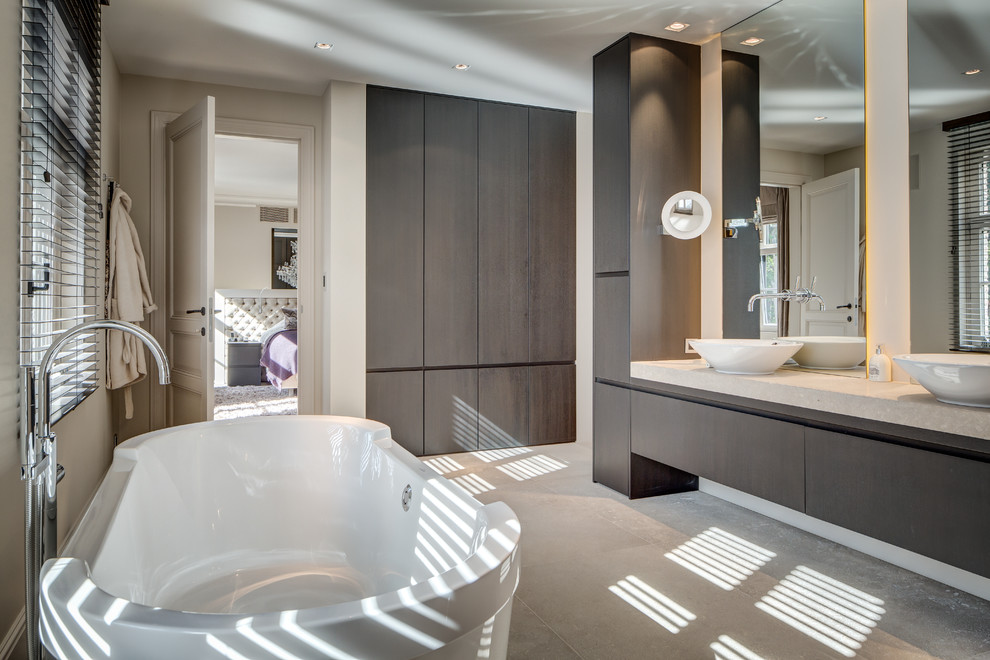 Inspiration for a contemporary bathroom in Other with flat-panel cabinets, dark wood cabinets, a freestanding tub, a vessel sink and white walls.