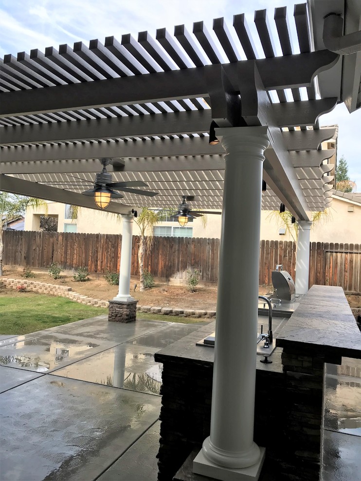 Inspiration for a large craftsman backyard concrete patio kitchen remodel with a pergola