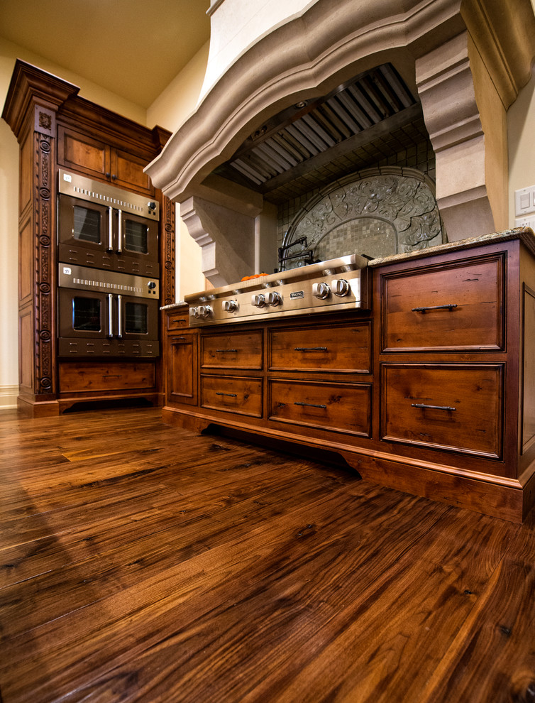 Photo of a medium sized classic kitchen/diner in Cleveland with raised-panel cabinets, medium wood cabinets, multi-coloured splashback, mosaic tiled splashback, stainless steel appliances, medium hardwood flooring and no island.