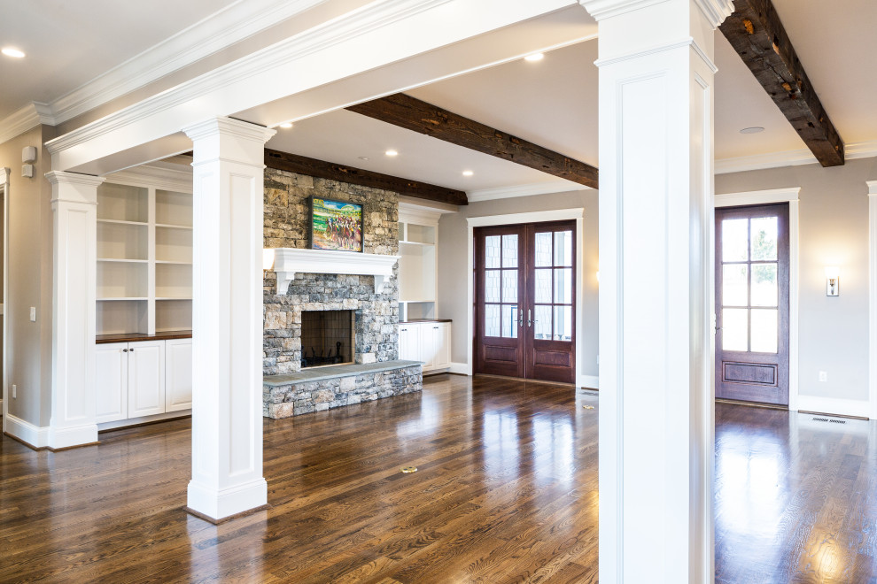 Country open concept living room in Other with beige walls, dark hardwood floors, a standard fireplace, a stone fireplace surround, a wall-mounted tv and exposed beam.