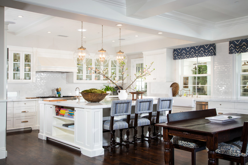 Photo of a large traditional u-shaped eat-in kitchen in Los Angeles with glass-front cabinets, white cabinets, white splashback, dark hardwood floors and with island.