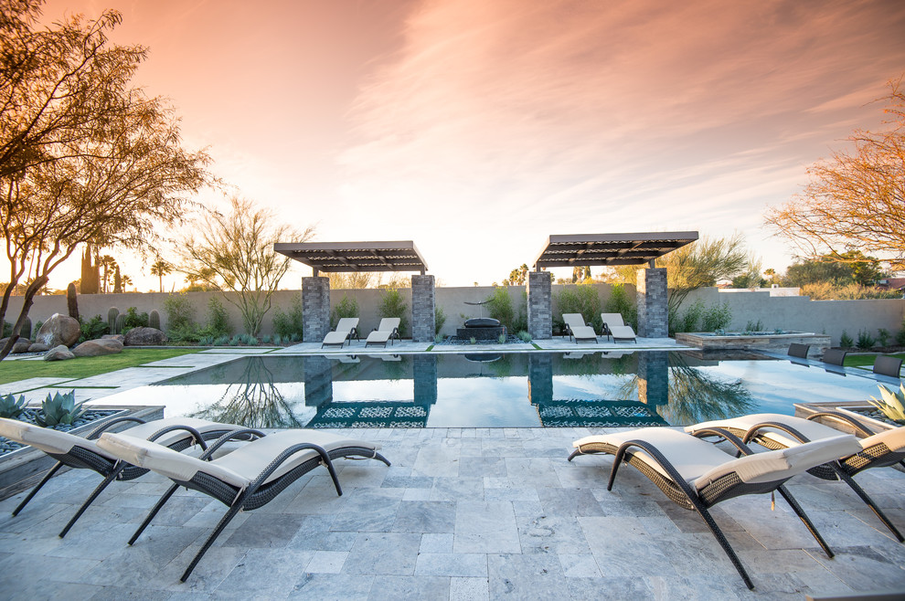 Photo of a large contemporary backyard rectangular infinity pool in Phoenix with stamped concrete.