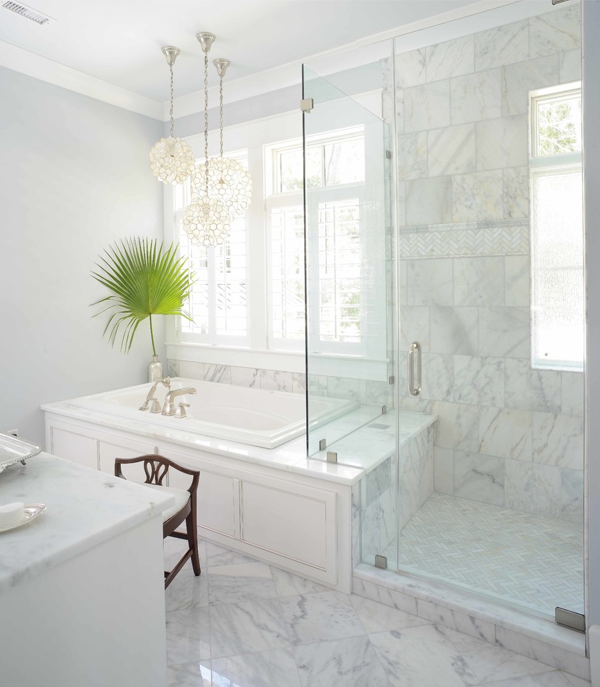 Photo of a mid-sized traditional master bathroom in Charleston with recessed-panel cabinets, white cabinets, a drop-in tub, a corner shower, a one-piece toilet, gray tile, ceramic tile, grey walls, marble floors, an undermount sink, granite benchtops, a hinged shower door and white benchtops.