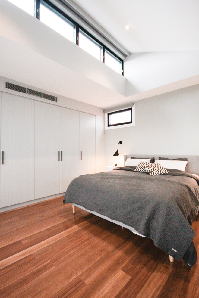На фото: хозяйская спальня в стиле модернизм с серыми стенами, паркетным полом среднего тона, коричневым полом и панелями на части стены