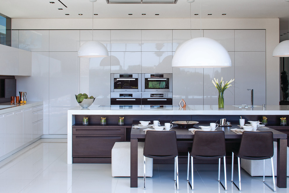 Photo of an expansive contemporary l-shaped open plan kitchen in Los Angeles with flat-panel cabinets, white cabinets, stainless steel appliances, with island, white floor and white benchtop.