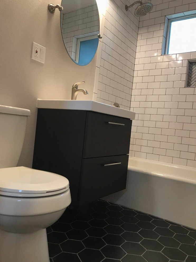 This is an example of a small midcentury 3/4 bathroom in Portland with flat-panel cabinets, black cabinets, an alcove tub, a shower/bathtub combo, a two-piece toilet, white tile, ceramic tile, grey walls, porcelain floors, an integrated sink, engineered quartz benchtops, black floor, a shower curtain and white benchtops.