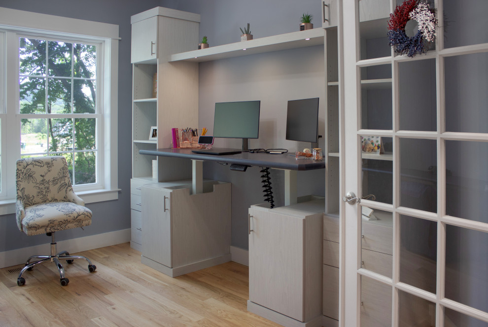Klassisk inredning av ett mellanstort arbetsrum, med blå väggar, ljust trägolv och ett inbyggt skrivbord