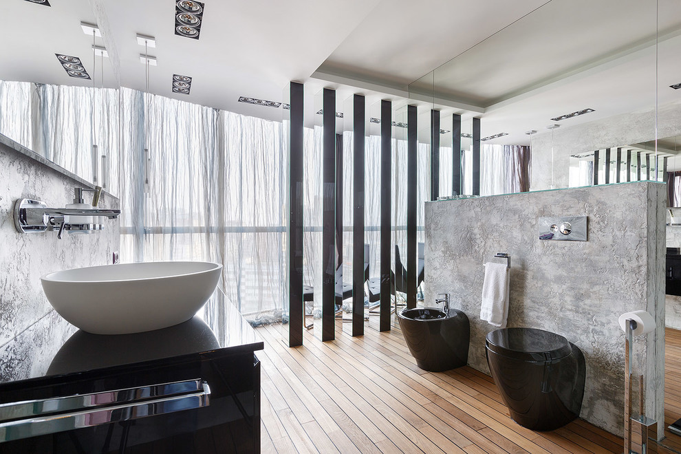 Photo of a mid-sized contemporary 3/4 bathroom in Saint Petersburg with flat-panel cabinets, black cabinets, grey walls, light hardwood floors, laminate benchtops, a bidet and a vessel sink.
