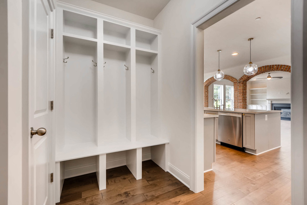 Inspiration for a large traditional mudroom in Baltimore with white walls, medium hardwood floors, a single front door, a white front door and brown floor.