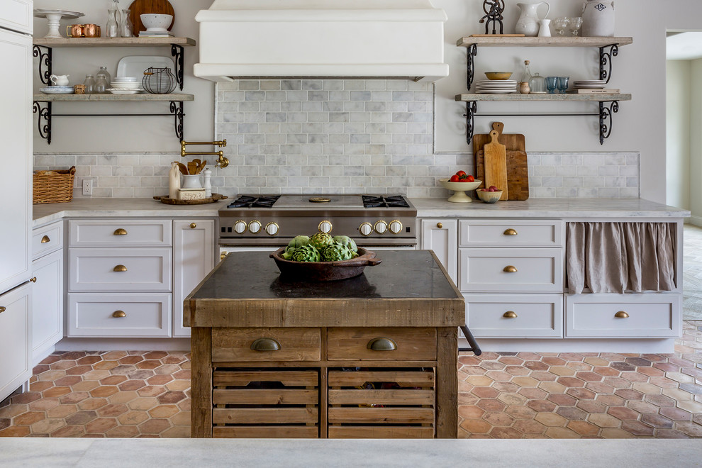 Inspiration for a mid-sized country galley open plan kitchen in San Diego with raised-panel cabinets, white cabinets, marble benchtops, grey splashback, ceramic splashback, stainless steel appliances, with island, a single-bowl sink, cement tiles and red floor.