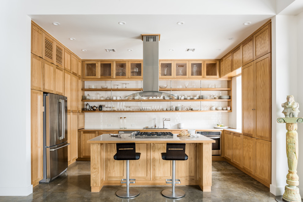 Inspiration for a mid-sized industrial kitchen in Houston with shaker cabinets, medium wood cabinets, stainless steel benchtops, white splashback, ceramic splashback, stainless steel appliances, concrete floors and with island.
