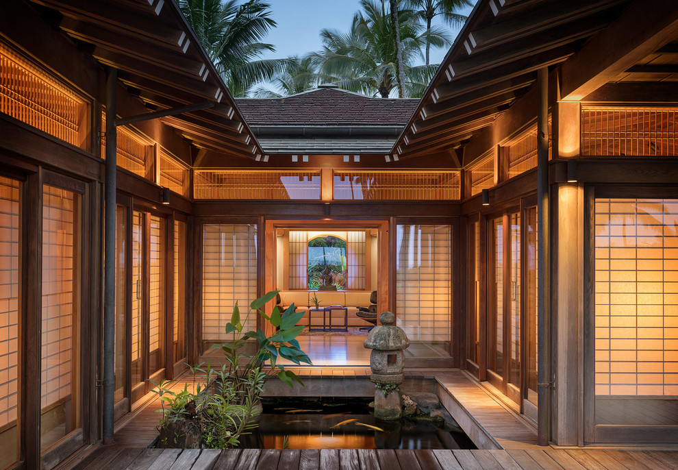 Inspiration for an expansive asian backyard deck in Hawaii with a water feature and a roof extension.