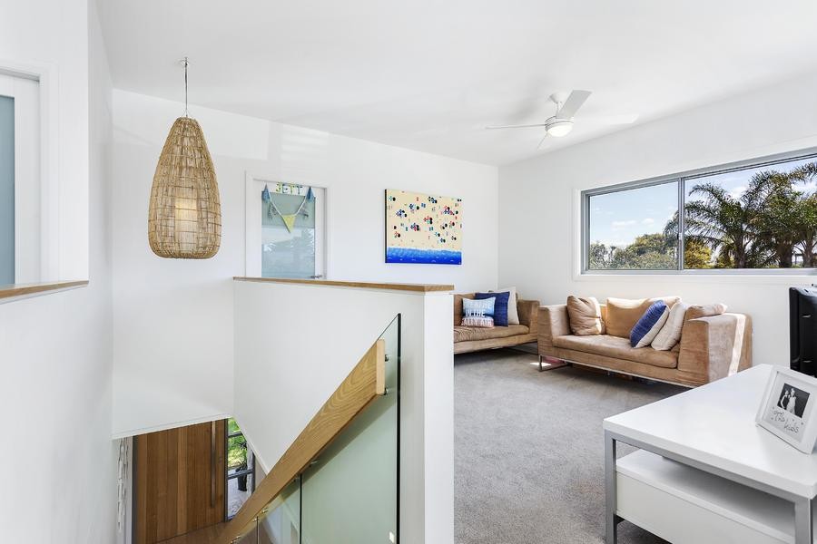 This is an example of a mid-sized beach style open concept family room in Sydney with white walls, carpet and a freestanding tv.