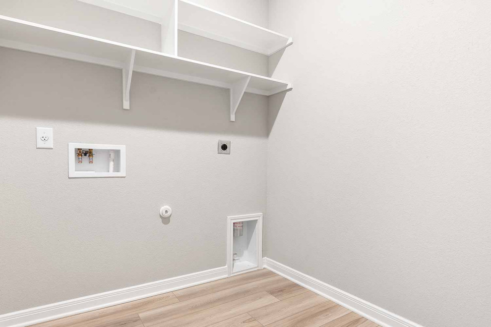 Foto på en mellanstor linjär tvättstuga enbart för tvätt, med öppna hyllor, vita skåp, grå väggar, vinylgolv, en tvättmaskin och torktumlare bredvid varandra och beiget golv