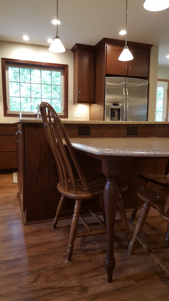 Example of a large transitional l-shaped vinyl floor eat-in kitchen design with an undermount sink, shaker cabinets, dark wood cabinets, quartz countertops, beige backsplash, subway tile backsplash, stainless steel appliances and an island