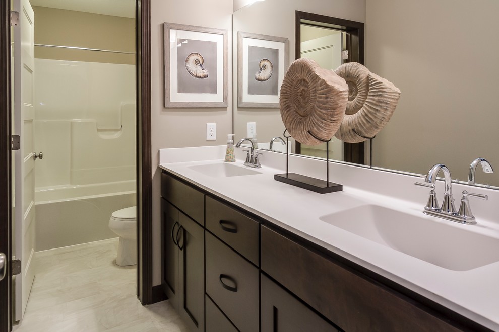Mid-sized transitional master bathroom in Minneapolis with shaker cabinets, dark wood cabinets, an alcove tub, a shower/bathtub combo, a two-piece toilet, beige tile, ceramic tile, beige walls, ceramic floors, an integrated sink and solid surface benchtops.