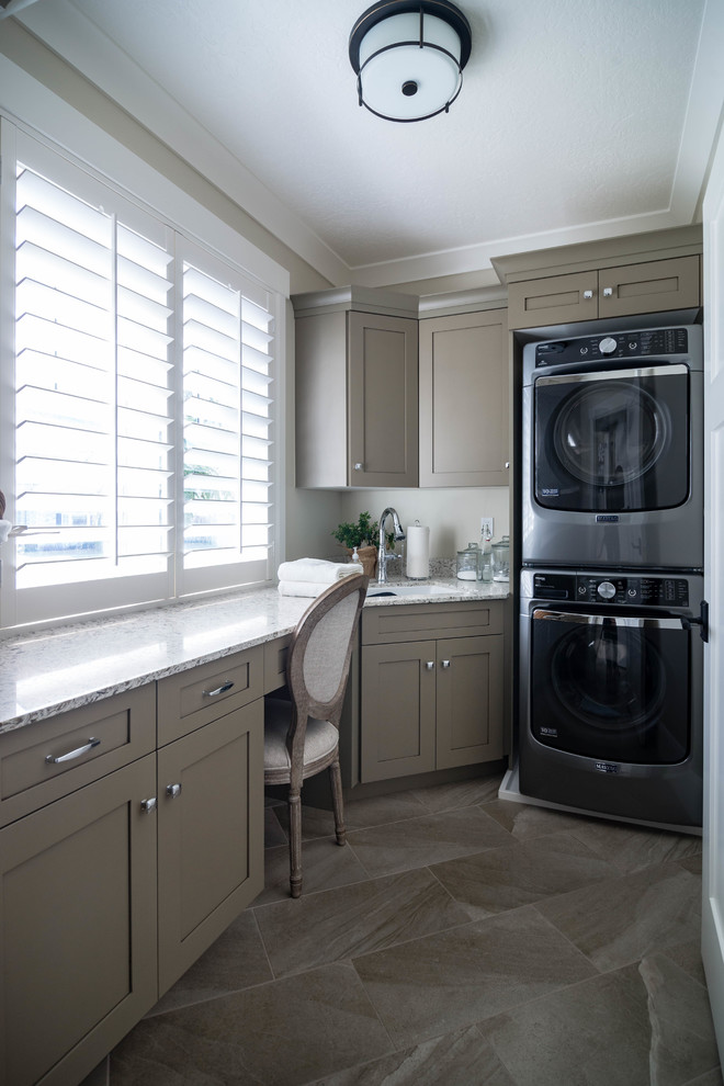 Design ideas for a mid-sized transitional single-wall dedicated laundry room in Salt Lake City with recessed-panel cabinets, brown cabinets, granite benchtops, beige walls, ceramic floors, a stacked washer and dryer, beige floor and an undermount sink.