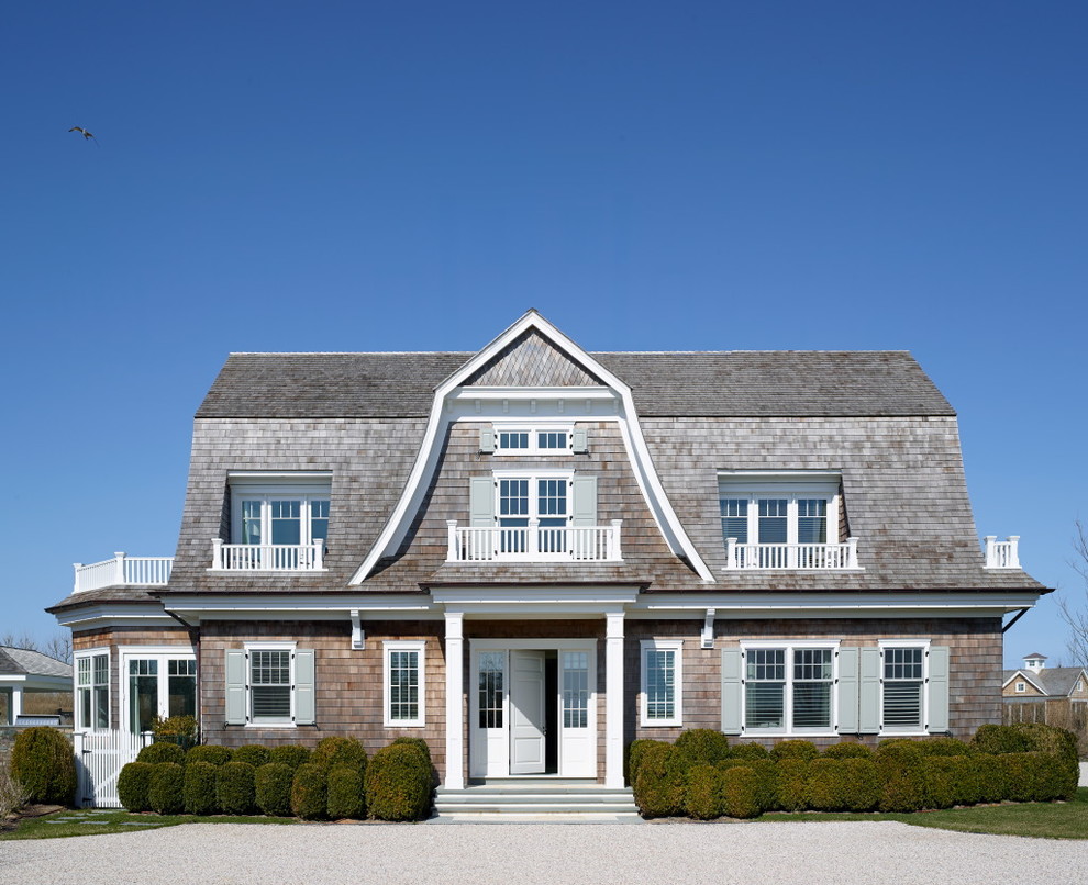This is an example of a large beach style two-storey brown exterior in New York with wood siding and a gambrel roof.