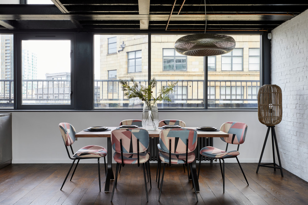 Medium sized industrial dining room in London with white walls, dark hardwood flooring, brown floors and brick walls.