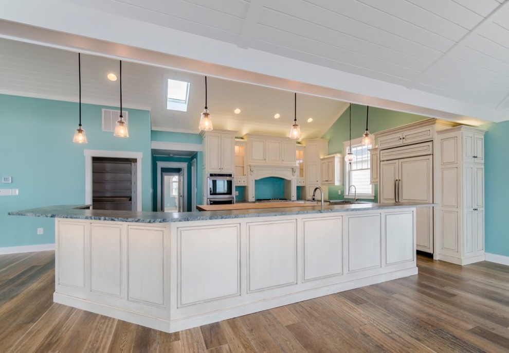 Kitchen - large transitional u-shaped dark wood floor and brown floor kitchen idea with a farmhouse sink, raised-panel cabinets, beige cabinets, blue backsplash, glass tile backsplash, paneled appliances, an island and gray countertops