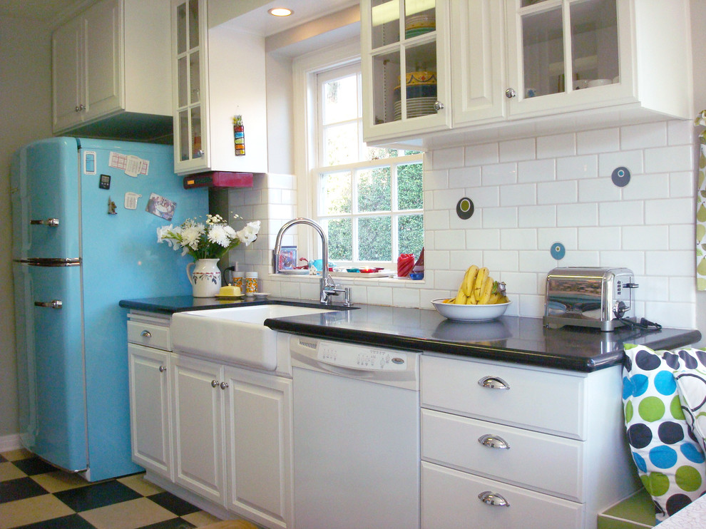 Photo of a mid-sized eclectic galley separate kitchen in Los Angeles with a farmhouse sink, white cabinets, white splashback, subway tile splashback, coloured appliances, glass-front cabinets, vinyl floors, quartz benchtops and no island.