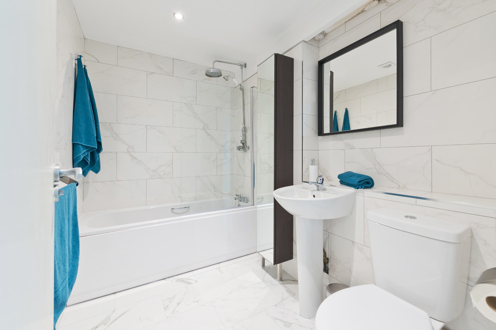 Design ideas for a mid-sized contemporary kids bathroom in Dublin with glass-front cabinets, black cabinets, a drop-in tub, a shower/bathtub combo, a two-piece toilet, white tile, porcelain tile, white walls, porcelain floors, a pedestal sink, tile benchtops and white floor.