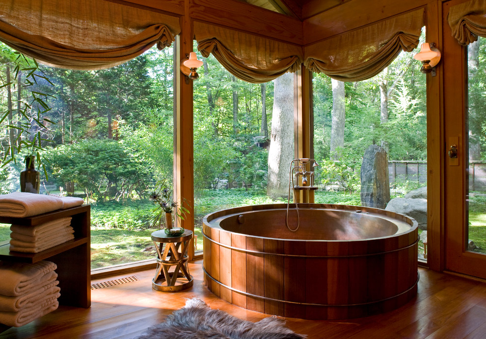Inspiration for an asian master bathroom in New York with a japanese tub, dark hardwood floors and brown floor.