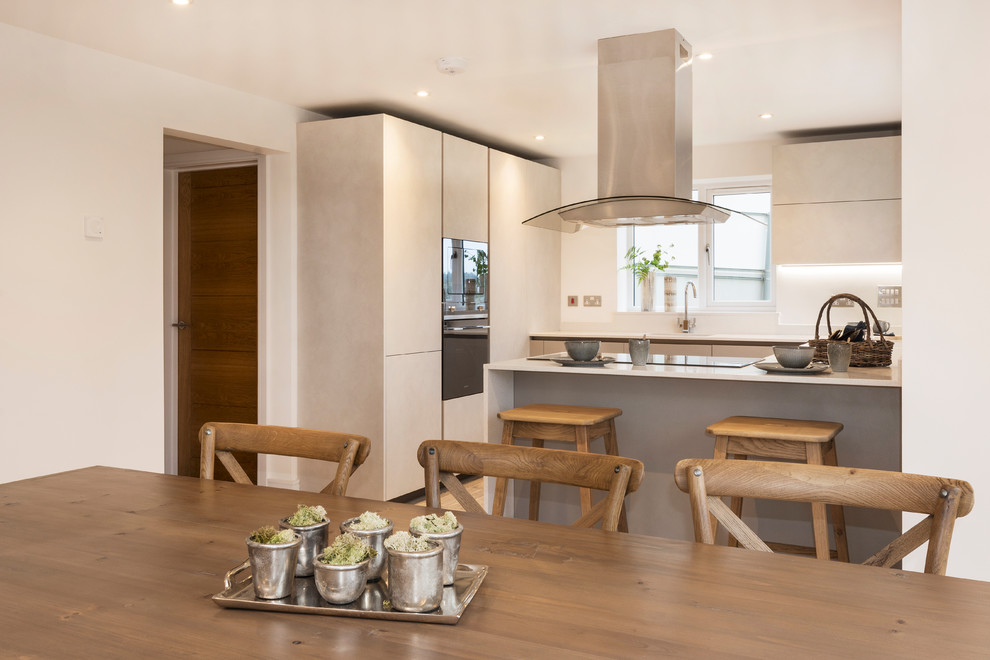This is an example of a mid-sized modern eat-in kitchen in Devon with a single-bowl sink, glass-front cabinets, blue cabinets, red splashback, stainless steel appliances, laminate floors, grey floor and white benchtop.