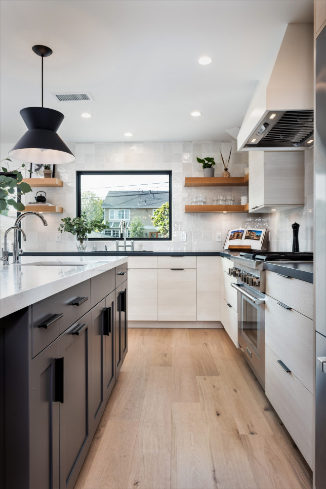 Foto på ett mellanstort kök, med en undermonterad diskho, släta luckor, vitt stänkskydd, rostfria vitvaror, ljust trägolv och en köksö