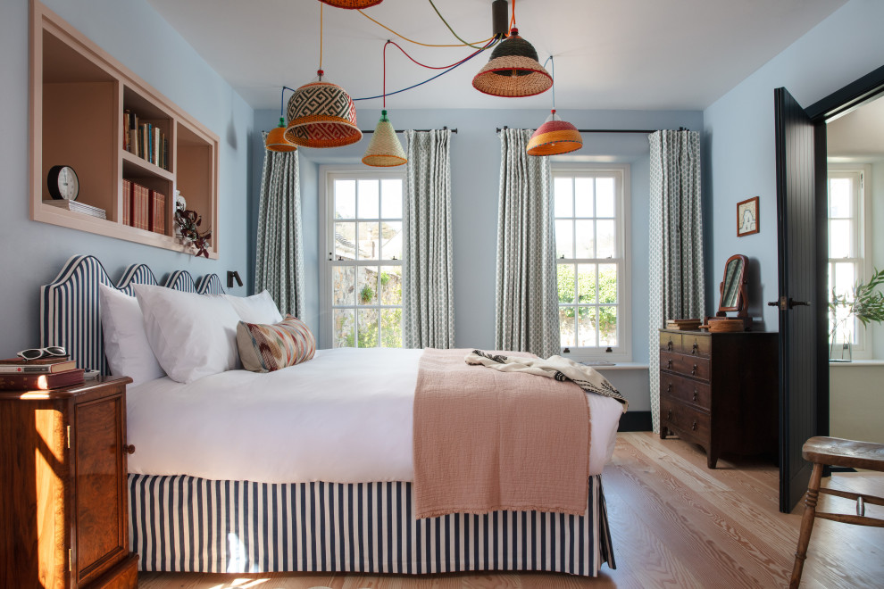 Bohemian bedroom in Cornwall with blue walls, light hardwood flooring and beige floors.