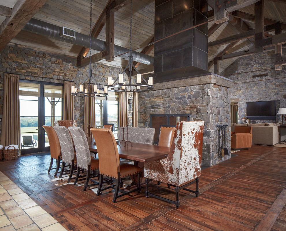Photo of a country open plan dining in Houston with dark hardwood floors and a stone fireplace surround.