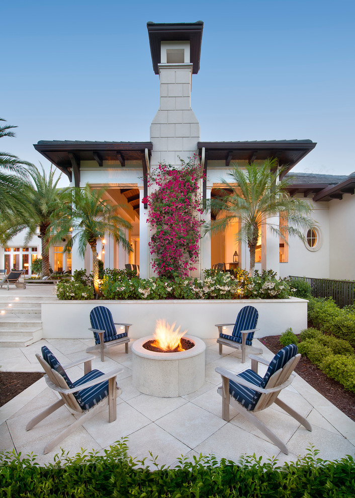 Inspiration for a large tropical backyard patio in Miami with a fire feature, no cover and natural stone pavers.