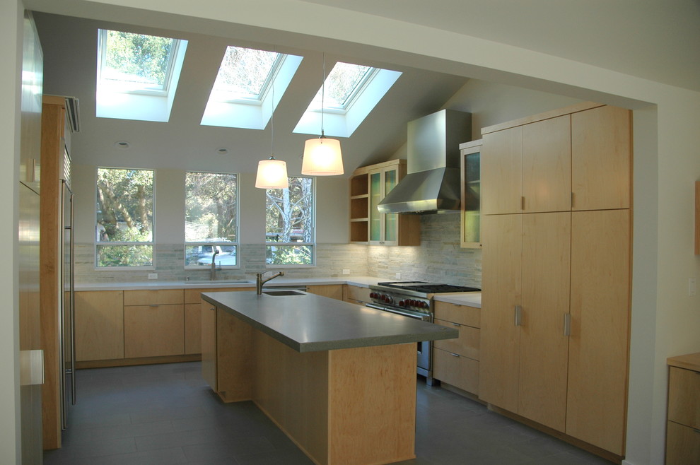 Design ideas for a modern u-shaped eat-in kitchen in San Francisco with an undermount sink, flat-panel cabinets, light wood cabinets, concrete benchtops, beige splashback, stone tile splashback, stainless steel appliances and with island.