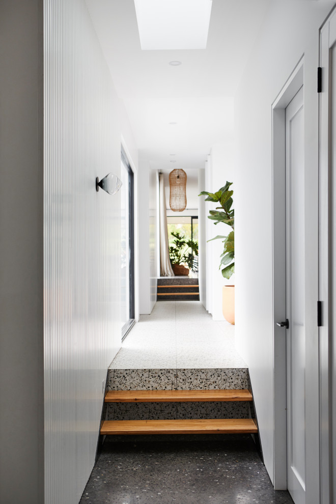 Large contemporary hallway in Other with white walls, concrete floors, black floor and panelled walls.