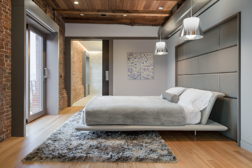 Photo of an industrial master bedroom in Boston with grey walls, light hardwood floors and no fireplace.