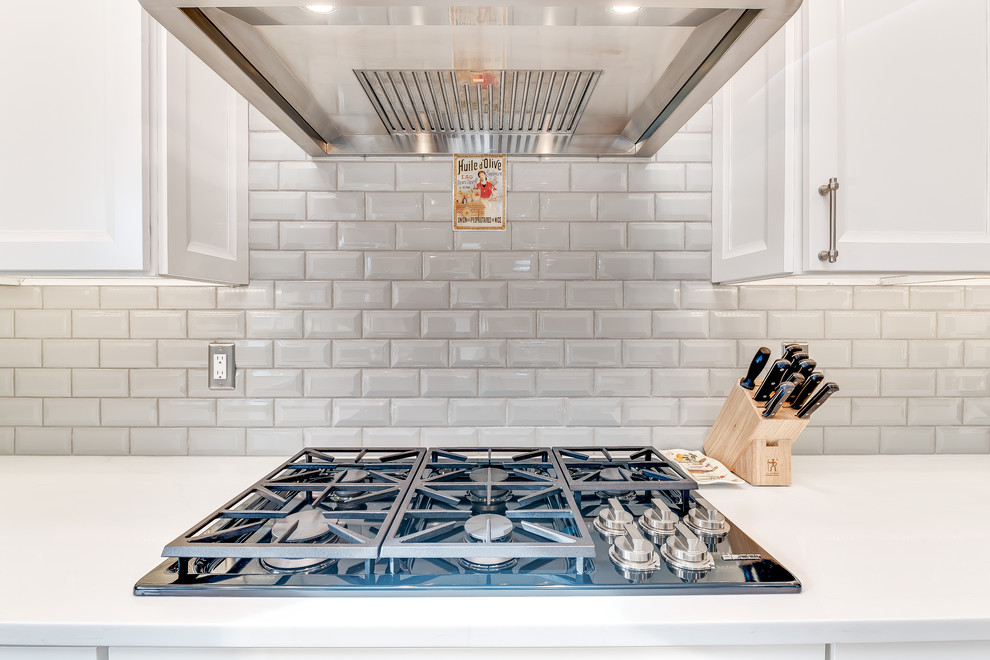 Mid-sized transitional u-shaped medium tone wood floor and brown floor eat-in kitchen photo in Boise with a farmhouse sink, shaker cabinets, white cabinets, quartz countertops, gray backsplash, subway tile backsplash, stainless steel appliances and an island