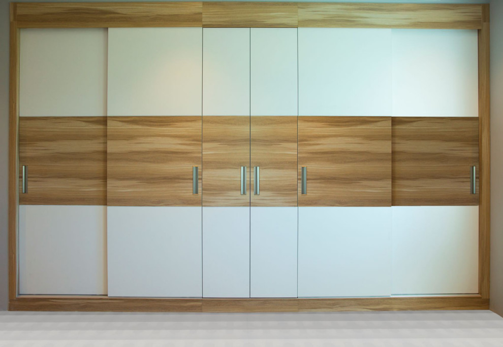 Idée de décoration pour une grande armoire encastrée design en bois clair neutre avec un placard à porte plane.