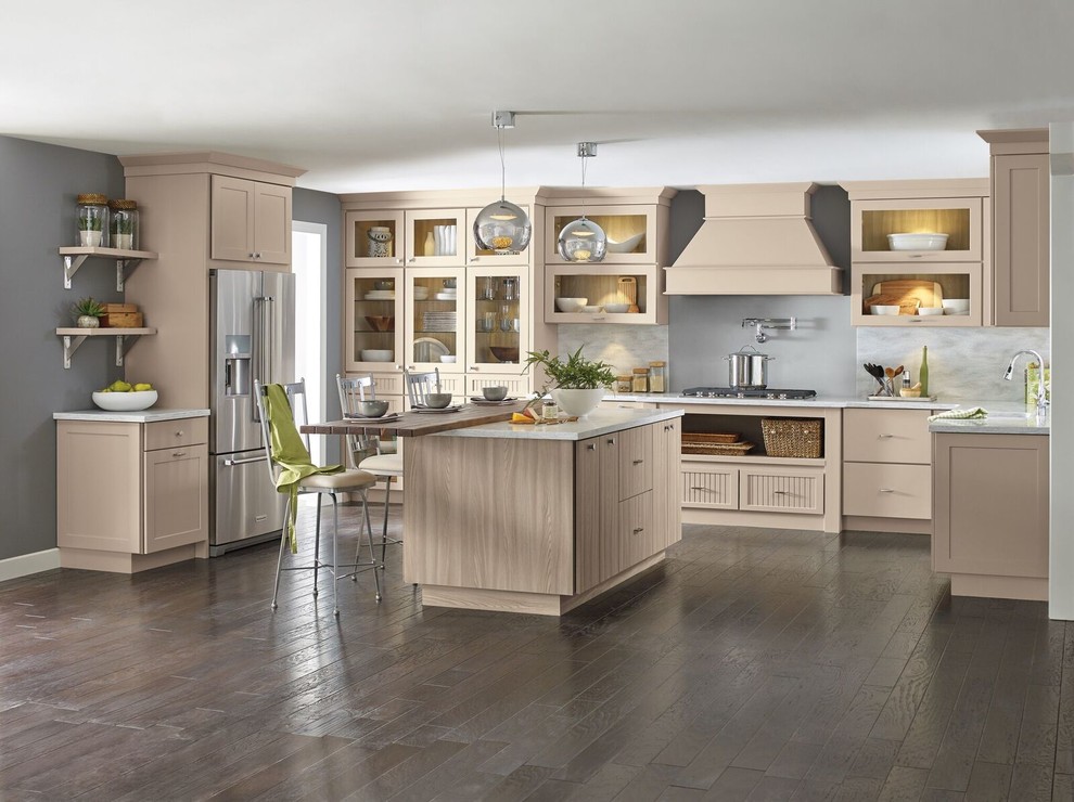 Mid-sized transitional l-shaped medium tone wood floor and brown floor enclosed kitchen photo with an undermount sink, glass-front cabinets, beige cabinets, marble countertops, gray backsplash, marble backsplash, stainless steel appliances and an island