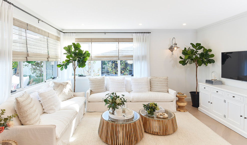 Photo of a large transitional open concept living room in Sydney with white walls, a wall-mounted tv and beige floor.