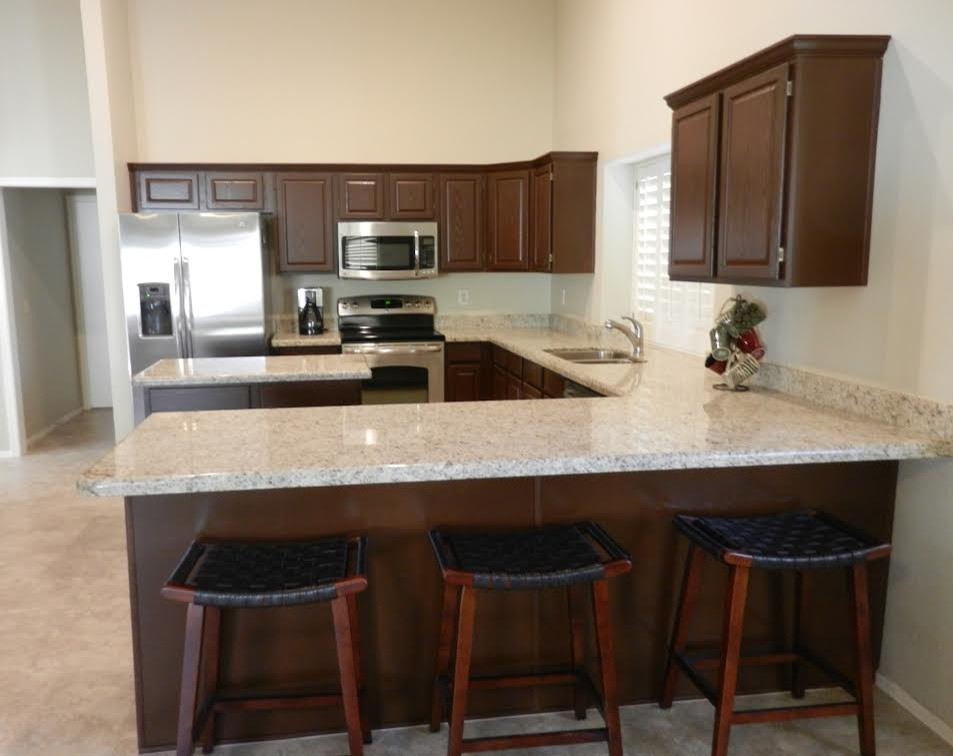 This is an example of a large traditional u-shaped separate kitchen in Phoenix with a double-bowl sink, raised-panel cabinets, dark wood cabinets, granite benchtops, stainless steel appliances, limestone floors and with island.