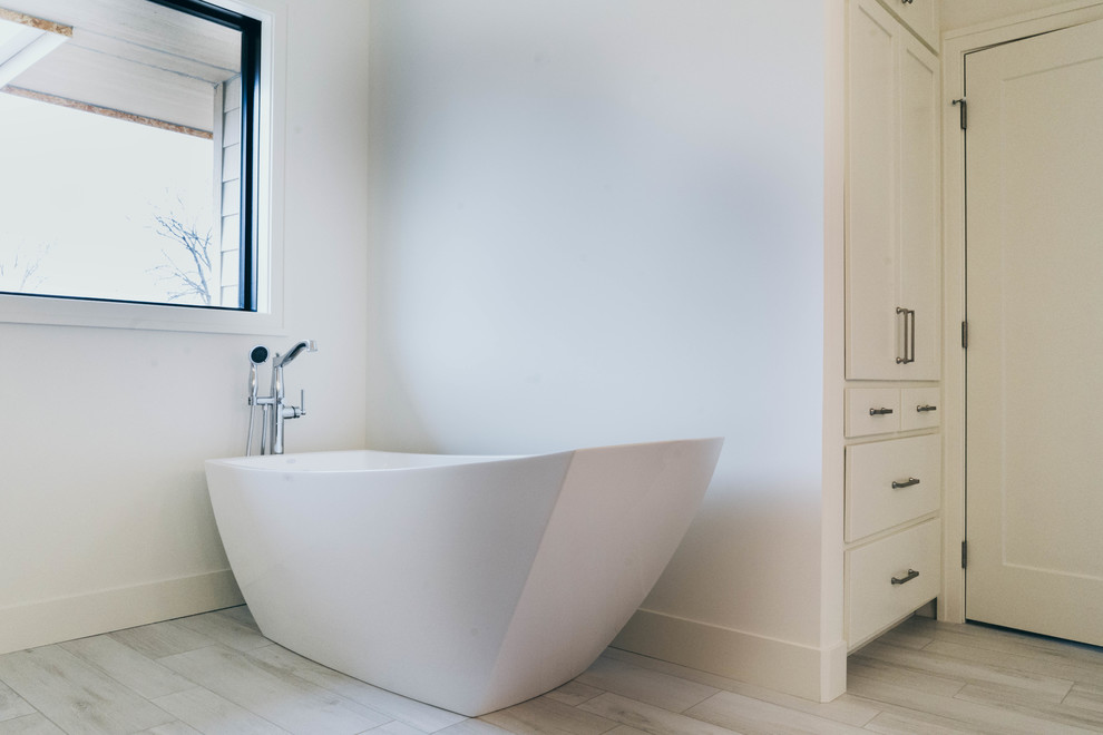 Freestanding bathtub - transitional master white tile freestanding bathtub idea in Omaha with shaker cabinets, white cabinets, a two-piece toilet, an undermount sink, quartz countertops and white countertops